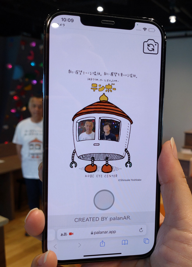 スマホ画面。テンボーの目（小窓）に男性と女性が表示されている。